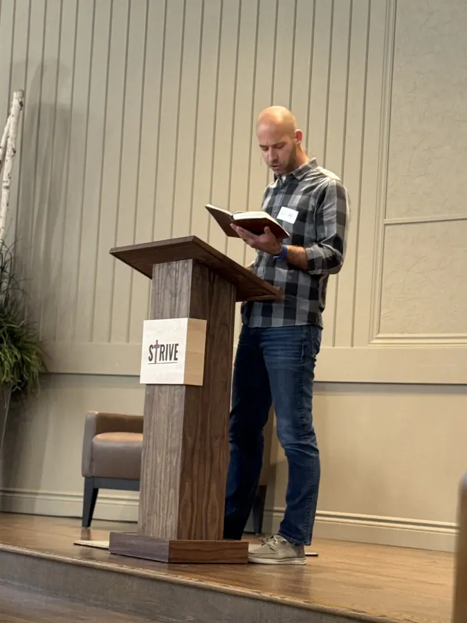 A man reading from the Bible at the Strive podium