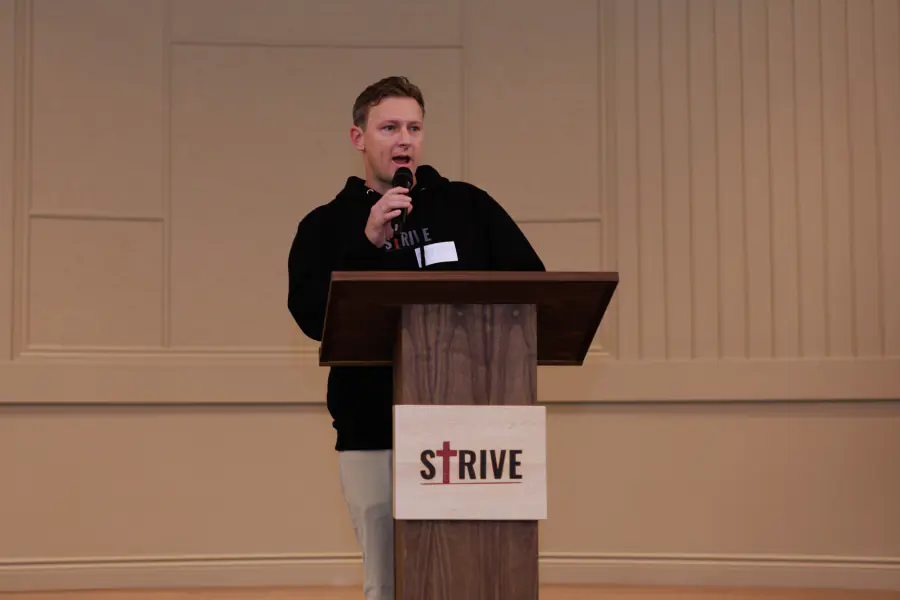 A Strive organizer welcoming attendees from the podium