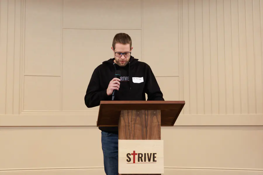 A Strive organizer reading at the podium