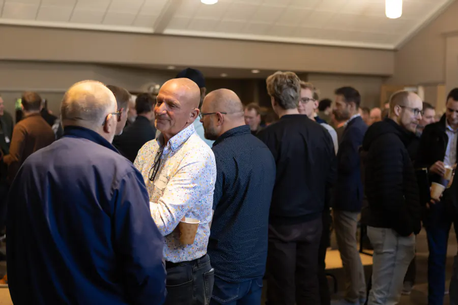 Men in conversation during a 2025 conference break
